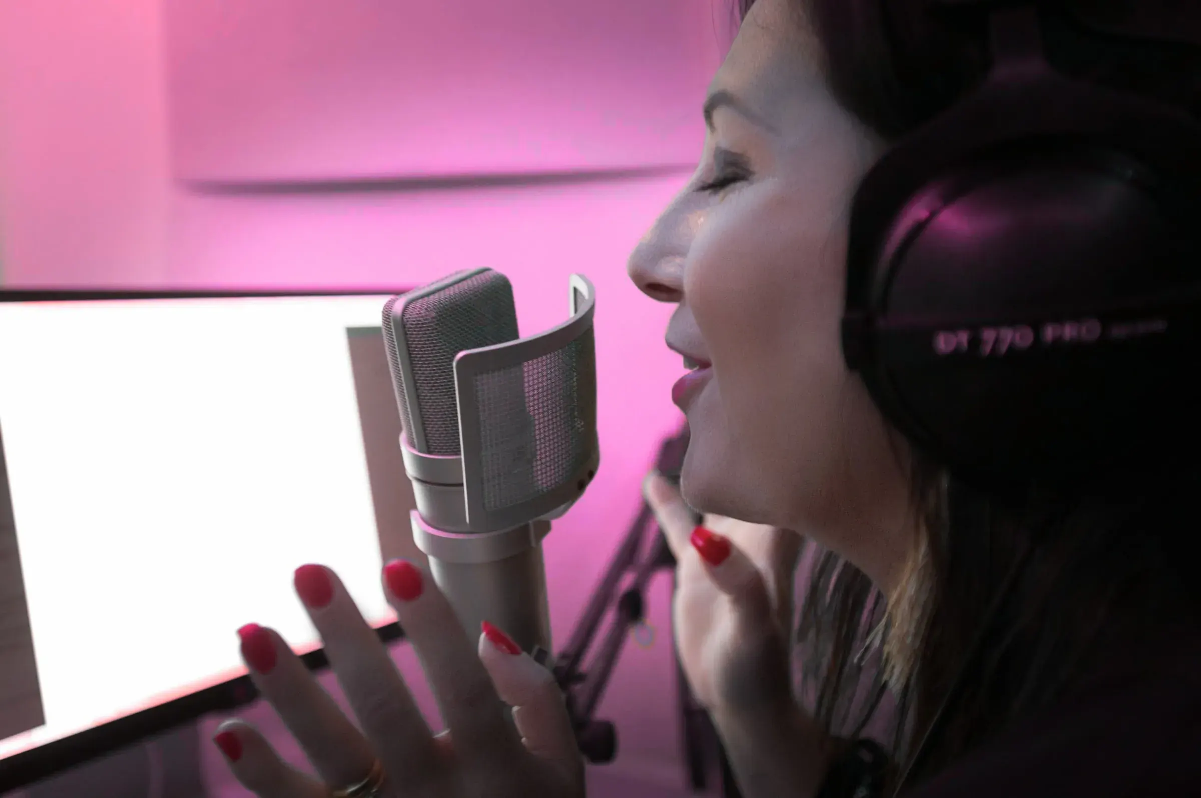 Estelle Hubert, comédienne voix off, au micro Neumann avec son casque Beyerdynamic DT 770 Pro, en lumière rose